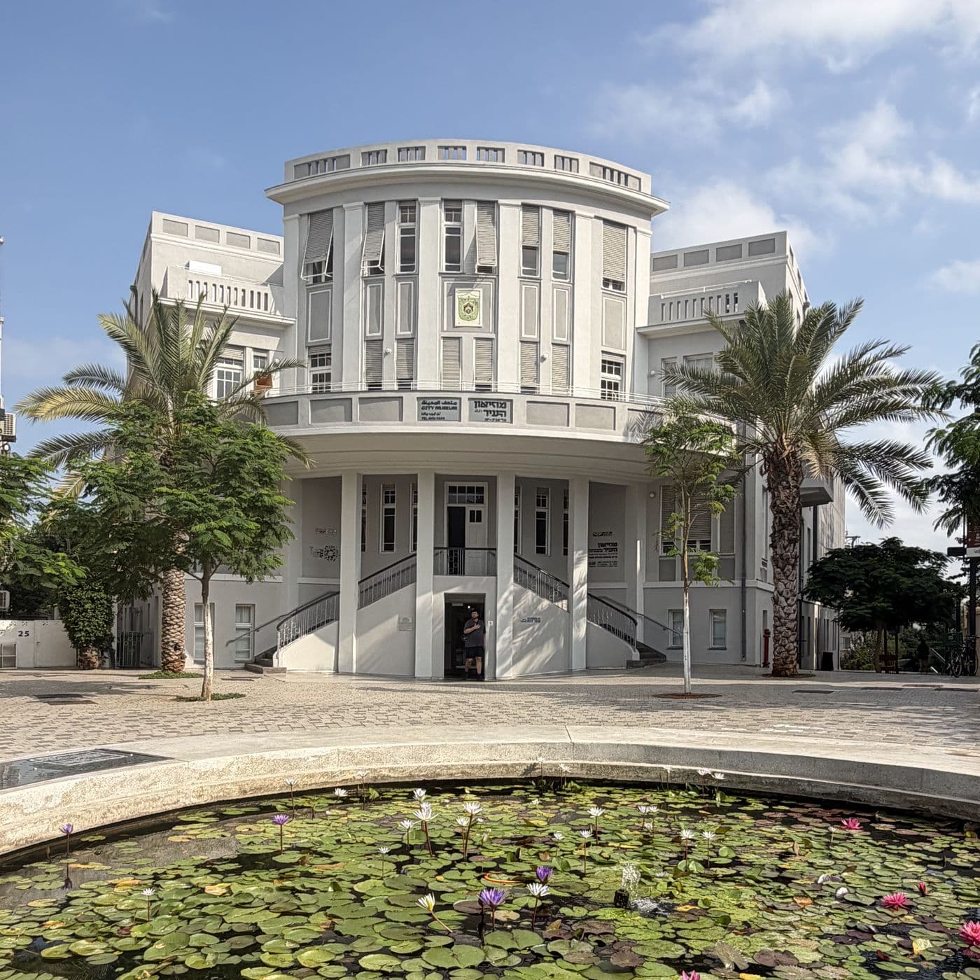 בית העיר בכיכר ביאליק, בניין לבן עם חזית מעוגלת ועמודים, בריכת נופרים בחזית