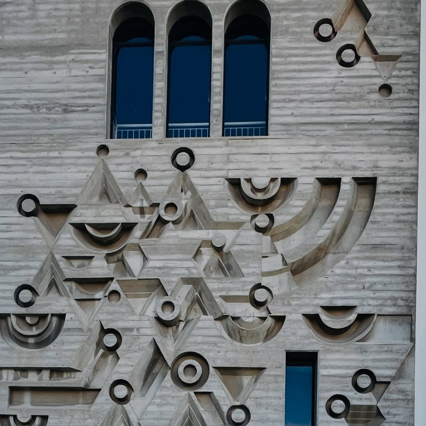 חזית בית כנסת בתל אביב, תבליטי בטון גיאומטריים במוטיבים יהודיים - מגן דוד ומנורה - סביב שלושה חלונות קשתיים
